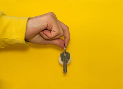 Hand holding keys on yellow background